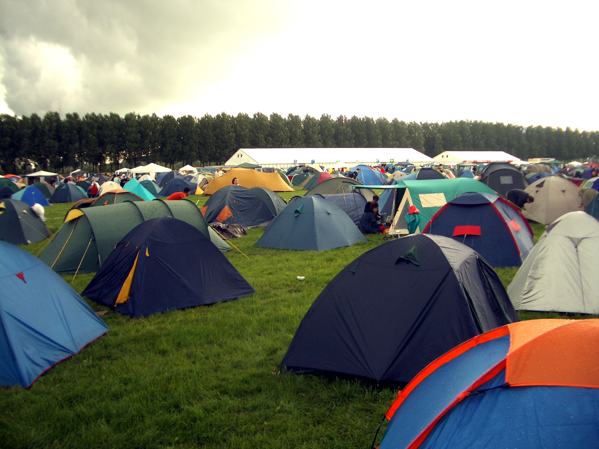 Rows of tents at a large outdoor festival campsite under blue skies