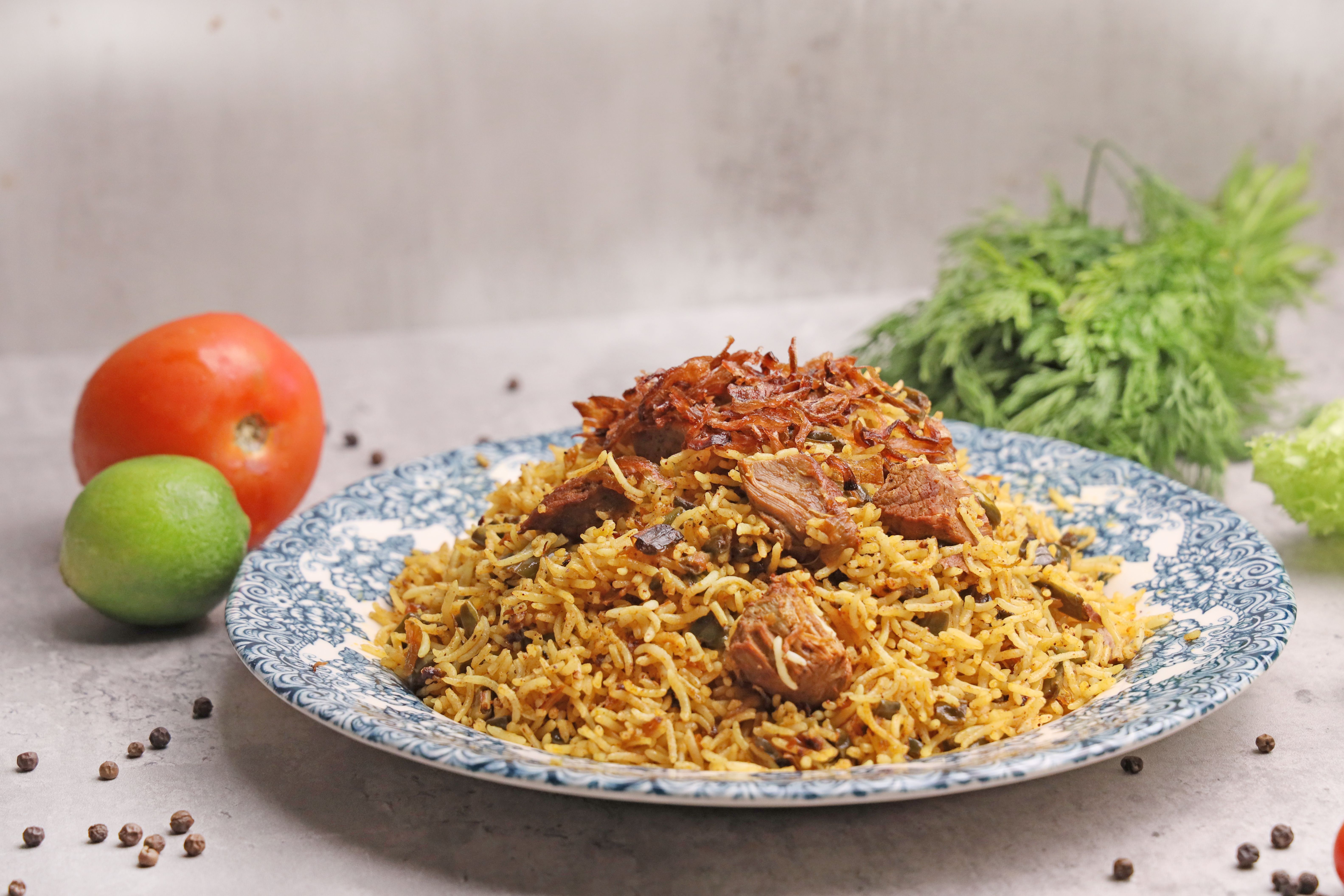 Lamb biryani served on a decorative plate with fresh vegetables, a Cape Malay-style curry meal
