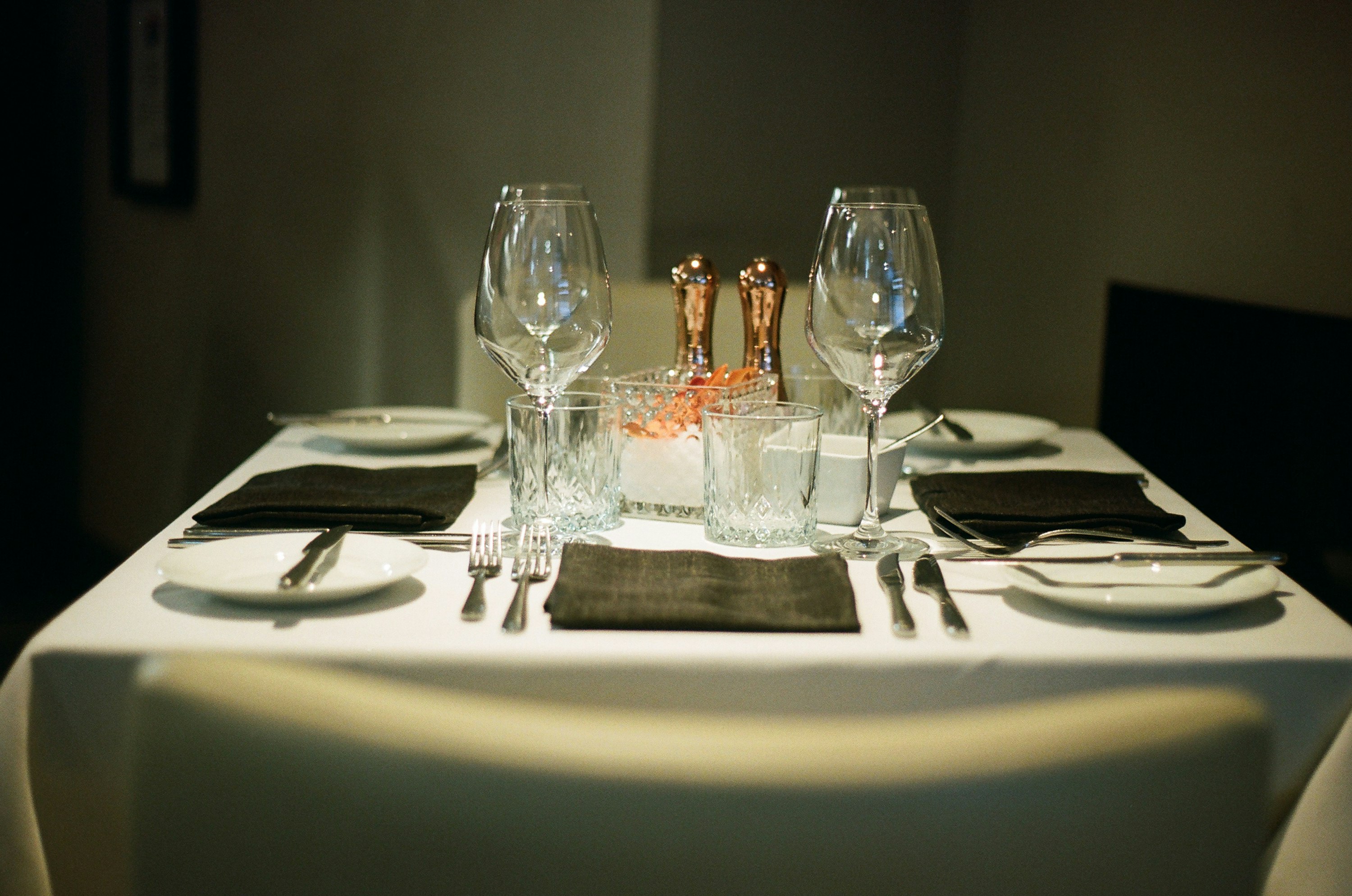 An elegantly set formal dining table with wine glasses and cutlery, representing premium hospitality service